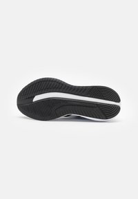 Black rubber shoe sole with textured tread pattern, featuring white accent line. The design focuses on traction and durability.