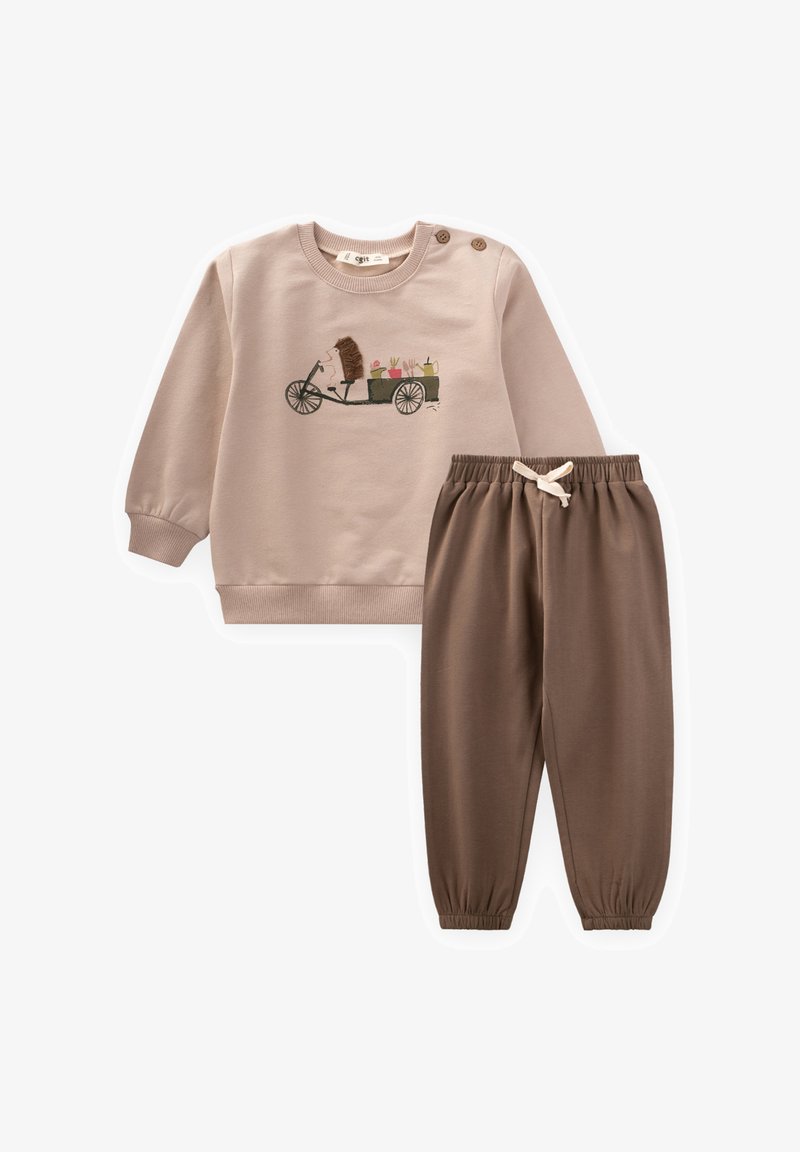 Bež sweatshirt s obliko ježa, sramni gumb na ramenih in rjavimi elastičnimi hlačami. Mehka bombažna tkanina, sproščen kroj, brez vzorcev.