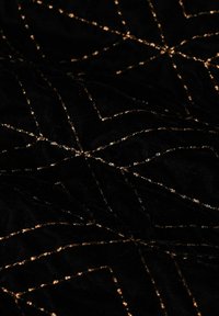 Zwart stof met een zachte textuur, met een geometrisch patroon van gouden stiknaden in een kruislings ontwerp.