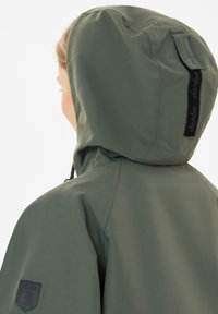 Hooded jack in olijf groen, met een gestructureerde buitenkant, verstelbare trekkoord bij de capuchon, en een logo patch op de mouw.