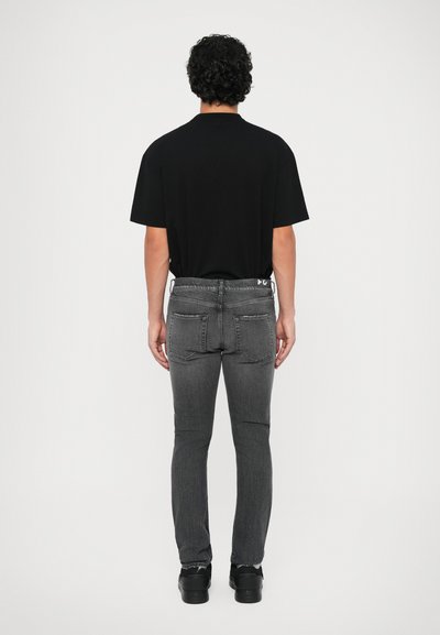 Svart t-shirt med kort ärm ihopparat med mörkgrå slim-fit jeans, med en subtilt urblekt textur, och svarta skor med en slät yta.