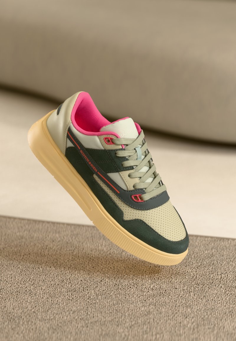Grüne und beige Sneaker mit pinken Akzenten, strukturiertem Wildleder und perforiertem Leder, ausgestattet mit einer klobigen Creme-Sohle und grünen Schnürsenkeln.