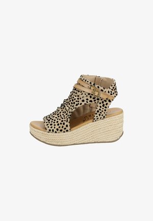 Sandale compensée beige avec des taches noires, bout ouvert, brides de cheville avec boucles dorées et semelle plateforme en corde tressée.