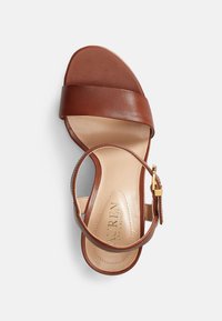 Brown leather heeled sandal with wide strap across the toes, adjustable ankle strap, and a tan leather insole featuring subtle branding.