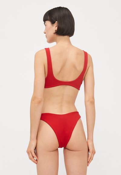 Červený bikiny set so širokými ramienkami a výstrihom do tvaru oka. S vysokým strihom na spodnej časti. Vyrobené z hladkej látky s minimálnymi švami.