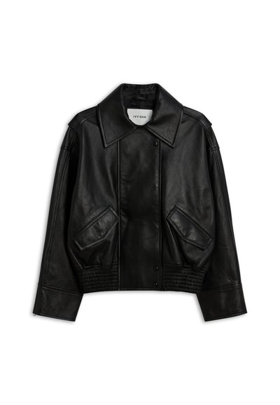 Crna jakna od umjetne kože s velikim ovratnikom, drukerima, dva prednja džepa pod kutom, elastičnim pojasom i dugim rukavima na bijeloj pozadini.