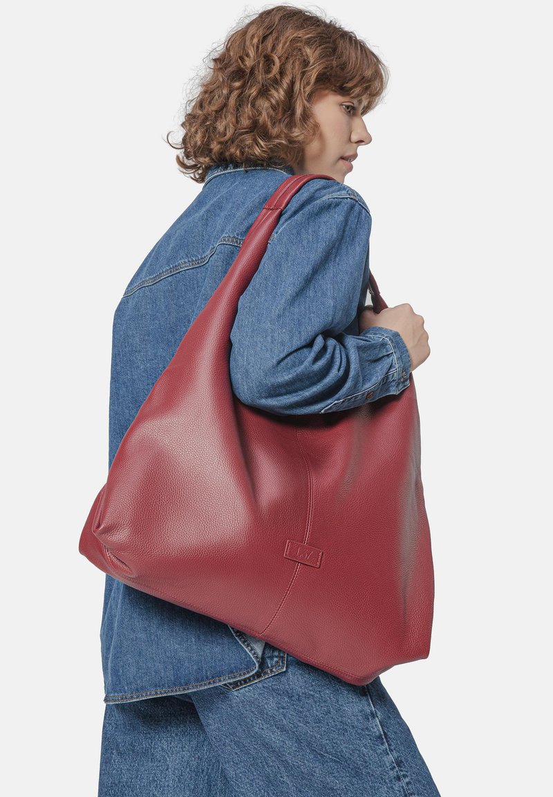 Sac à épaule en cuir rouge avec une texture galet, présentant un grand design souple et un accent logo subtil à l'avant.