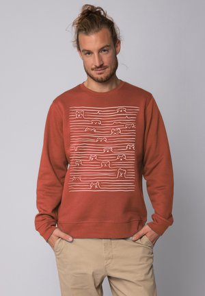 Bruine sweatshirt gemaakt van katoen, met een witte grafiek van gestileerde honden tegen horizontale lijnen. Lange mouwen en een ronde hals ontwerp.