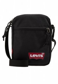 Bolso bandolera negro de Levi’s con bolsillo frontal con cremallera, correa ajustable y logo rojo de Levi’s en el panel inferior delantero.