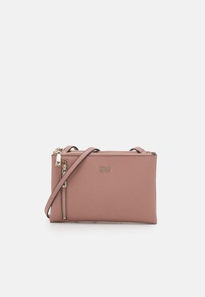 Petit sac bandoulière rectangulaire rose avec une poche zippée à l'avant, une quincaillerie dorée et le logo Guess embossé sur le devant.