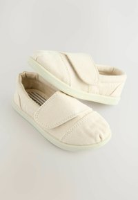 Canvas Slipper in Off-White mit minimalistischem Design, ausgestattet mit einem Klettverschluss und strukturiertem Obermaterial sowie einer Gummisohle.