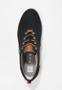 Herrarnas marinblå kanvas sneakers med bruna snören, läderdetaljer, metallögon och märkeskudde, sedd ovanifrån på vit bakgrund.