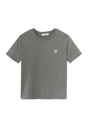 T-shirt gris à manches courtes en coton doux, présentant un petit emblème en cœur doré texturé sur le côté gauche de la poitrine.