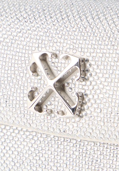 Ασημένιο μεταλλικό λογότυπο με τέσσερα αγκιστρωτά χέρια σε υφή επιφάνειας καλυμμένη με μικρές, λαμπερές, καθαρές στρας.