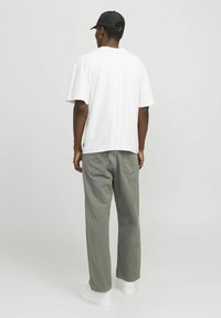 Witte T-shirt met korte mouwen, losse pasvorm. Gecombineerd met olijfgroene rechte broek. Witte sneakers en zwarte pet met verstelbare band.