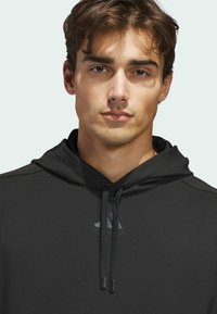 Black athletic hoodie with drawstrings, featuring a smooth texture and subtle logo detail on the chest, designed for comfort and performance.
