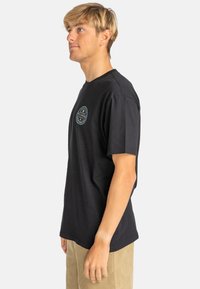 Black cotton t-shirt with short sleeves, a round neckline, and a circular multicolored logo on the chest. Smooth texture, relaxed fit.