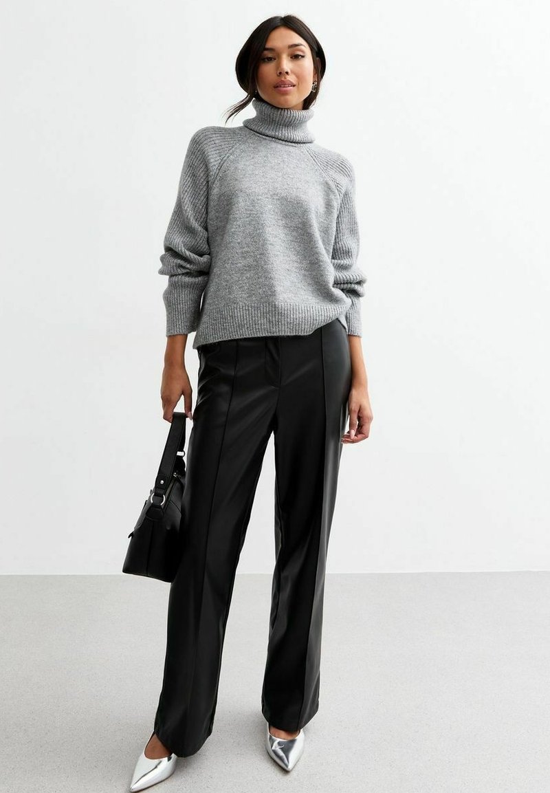 Szary, dziany sweter z golfem w połączeniu z eleganckimi czarnymi spodniami z sztucznej skóry oraz srebrnymi butami na szpilkach. Czarna torebka dopełnia outfit.