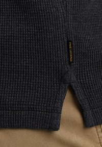 Dunkelgrauer Strickpullover mit einem strukturierten Muster und seitlichen Schlitzen. Enthält ein sichtbares "PME Legend"-Label. Der Hintergrund zeigt khakifarbenen Stoff.