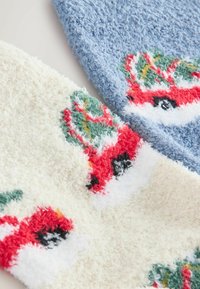 Sosete pufoase de culoare albastru deschis și crem. Soseta albastră are un model de mașini roșii, verzi și negre, în timp ce soseta crem are un design similar.