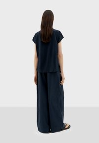 Marineblaues zweiteiliges Outfit mit einem kurzärmeligen Oberteil und weiten Hosen, aus weichem Stoff gefertigt, mit lockerer Passform und minimalistischem Design.