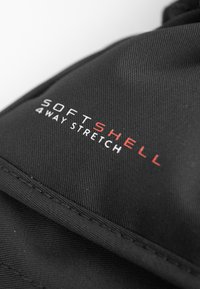 Schwarzer Softshell-Stoff mit rotem "SOFTSHELL 4 WAY STRETCH"-Logo. Verfügt über eine strukturierte Oberfläche und sichtbare Nahtdetails.