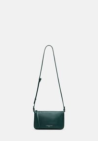 Ciemnozielona skórzana torba na ramię z regulowanym paskiem i logo „Liebeskind Berlin” na przedniej stronie na jednolitym jasnym tle.