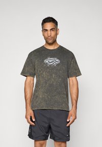 Olivengrøn tie-dye bomulds t-shirt med rund hals og korte ærmer, prydet med et gråt Nike-logo design på brystet.