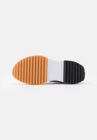 Rubber sneaker outsole with ridged texture. Color gradient from orange to white and black. Durable design with contrasting elements.