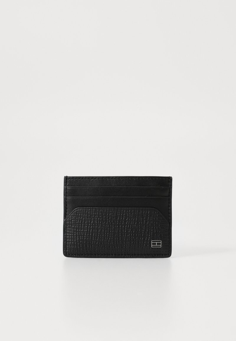 Black leather card holder with textured finish, featuring four card slots and a central pocket. Minimalistic design with subtle hardware detail.