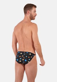 Schwarze Badehose mit einem bunten Planetenmotiv, das mehrere Himmelskörper vor einem sternengeschmückten Hintergrund zeigt. Glatte Textur.