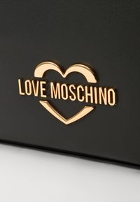 Black faux leather surface features a gold metallic "LOVE MOSCHINO" logo with a heart accent, offering a sleek, modern design.