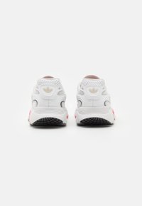 Bílé sportovní boty s růžovými detaily. Síťovaný a syntetický svršek, texturovaná opora paty a gumová podrážka s vzorovaným dezénem.