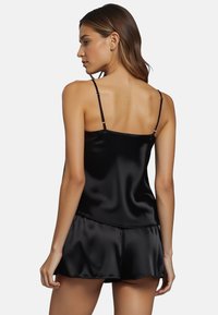 Camisole en satin noir avec des bretelles fines et un short assorti. Le tissu est lisse avec une légère brillance, présentant une coupe décontractée et un design simple.