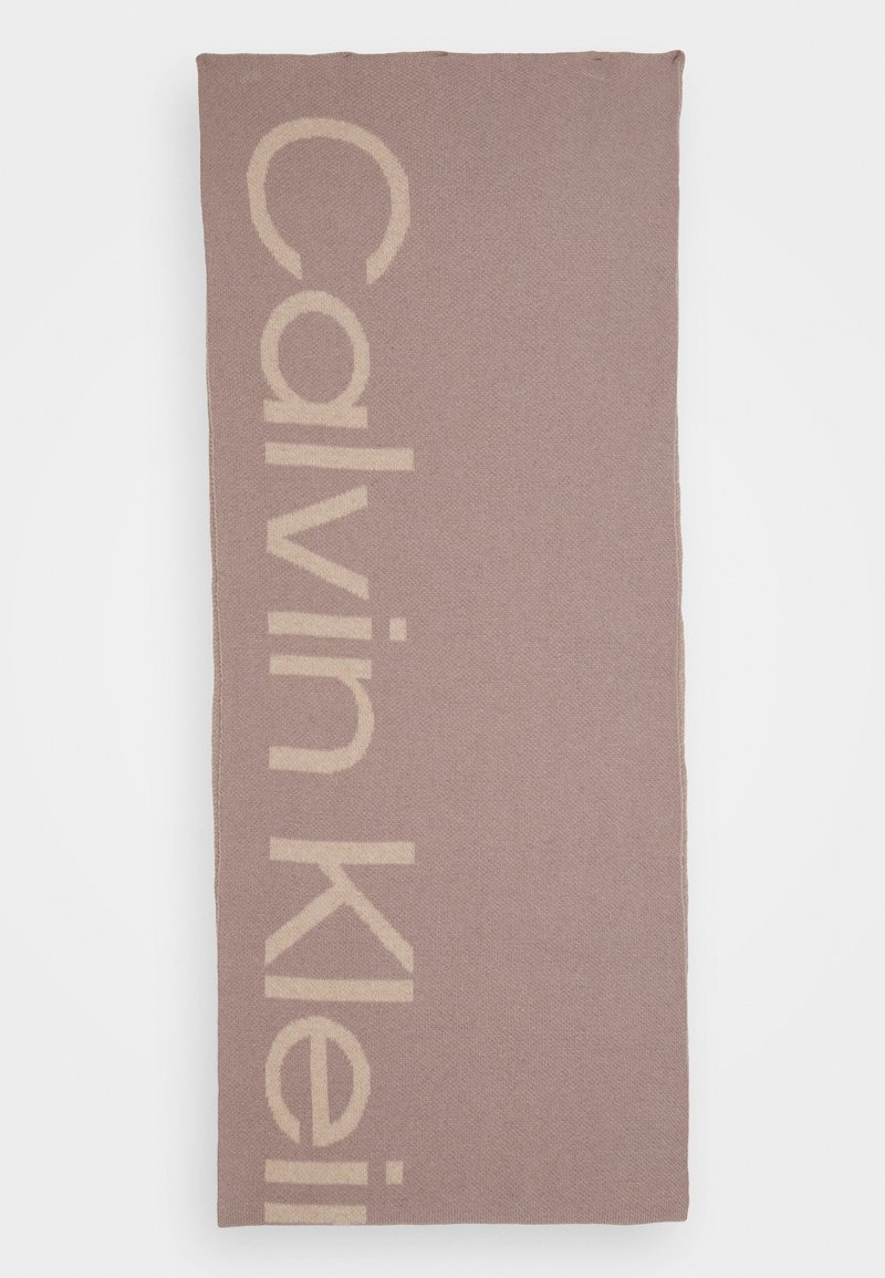 Écharpe rectangulaire mauve clair avec logo Calvin Klein beige aligné verticalement sur un côté, exposée à plat sur un fond blanc.