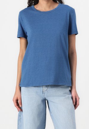 Blaues Baumwoll-T-Shirt mit kurzen Ärmeln, rundem Ausschnitt, lockerer Passform und leicht strukturierter Stoff. Kombiniert mit hellblauen Jeans.