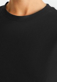 Sort bomulds T-shirt med rund halsudskæring og en glat tekstur. Stoffet virker let med minimale sømme og finish.
