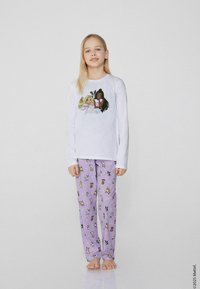Bílý dlouhý rukáv top s barevnou grafikou postavy. Fialové pyžamové kalhoty s různými vzory kreslených psů. Měkký bavlněný materiál.