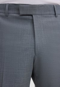 Grijze, op maat gemaakte broek met een gestructureerde stof, voorzien van een platte voorkant, riemlussen en een plooi die in het midden van elk been loopt.