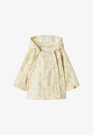 Imperméable léger jaune pâle avec un motif floral en rose et vert. Il possède une capuche, des poignets froncés et une patch logo visible sur l'ourlet.