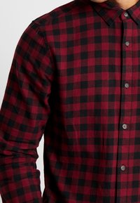Rood en zwart geruite flanellen shirt met een klassieke kraag, lange mouwen en knoopsluiting aan de voorkant. Kenmerkt zich door een soepele textuur en een reguliere pasvorm.