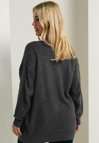 Dunkelgrauer, übergroßer Strickpullover mit strukturiertem Muster, weitem Ärmeln und lockerer Passform, von hinten betrachtet.