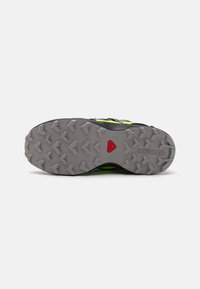 Rubber hiking shoe outsole with deep lugs for traction. Predominantly grey with red and black accents. Durable and rugged texture.