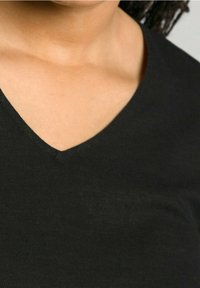 Haut noir à col en V, présentant une texture de tissu douce. L'encolure est nette et bien définie, avec des coutures soignées le long des bords.