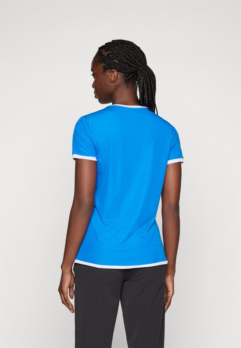 Blauwe sportieve t-shirt met korte mouwen, witte afwerking langs de kraag en mouwen, met een soepele textuur. Draagt met donkere broeken.