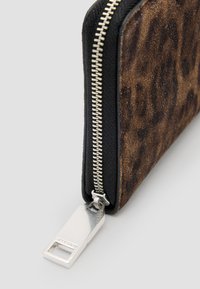 Cartera de piel de imitación de leopardo en tonos marrón y negro, con un zipper plateado y un tirador metálico rectangular para facilitar su apertura.