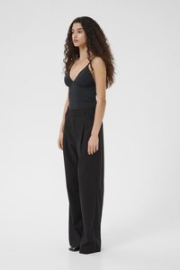 Černý top bez rukávů s hlubokým výstřihem do V, doplněný o černé kalhoty s vysokým pasem. Tento outfit se vyznačuje elegantním, přiléhavým střihem.