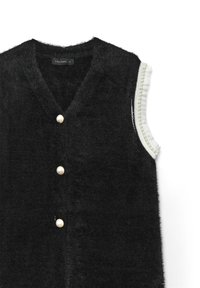 Gilet nero peloso senza maniche con scollo a V, tre bottoni di perla sul davanti e ricamo di volant bianchi con perle lungo il bordo delle aperture per le braccia.