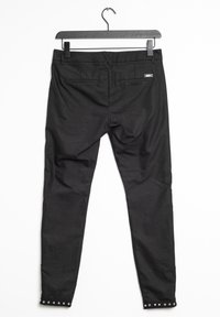 Svarta byxor med slim fit, som har ett midjeband, två bakfickor och nitar vid ankelsömmen. Slät textur, justerbart midjeband.