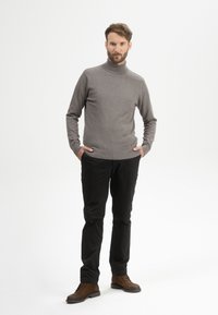 Grau turtleneck Pullover, glatte Textur, kombiniert mit schwarzen Hosen und braunen Schnürstiefeln. Schlichtes Design mit einer taillierten Silhouette.